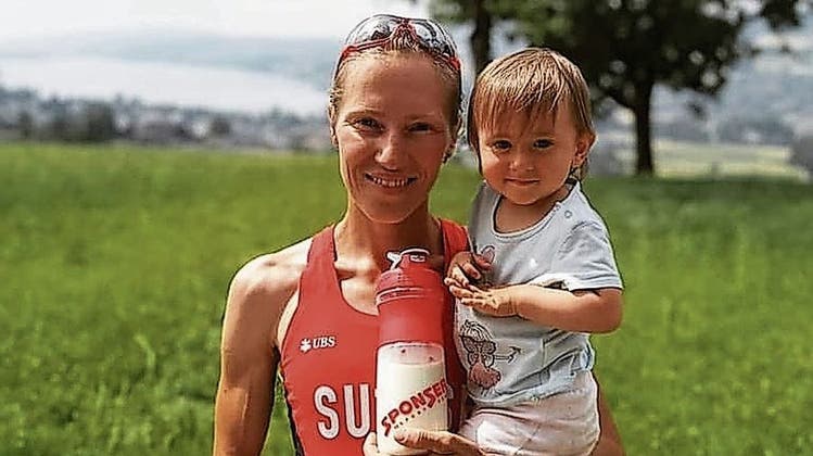Natalia Gemperle präsentiert sich stolz im Nationaldress des Schweizer Berglaufteams und mit Tochter Luna im Arm . (ZVG)