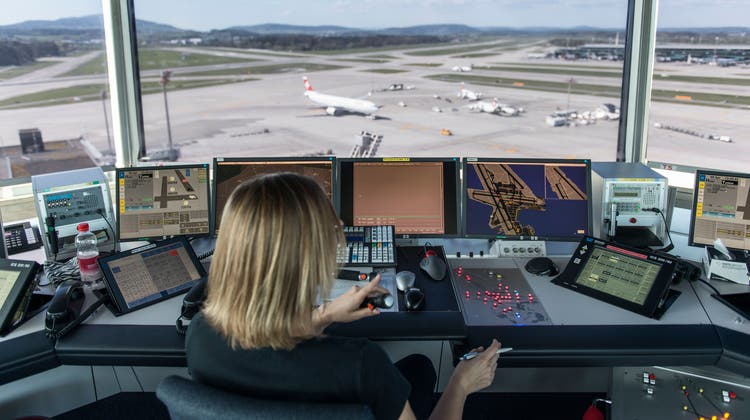 Eine Mitarbeiterin von Skyguide kontrolliert die Monitore und hat Blick auf das Flugfeld des Flughafens Zürich. (Bild: Christian Beutler / KEYSTONE)