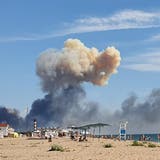 Rauch steigt auf aus der russischen Luftwaffenbasis «Saki» auf der Krim. In Sichtweite machen russische Touristen Ferien. (Bild: AP)