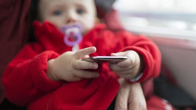 Handys oder Tablets sind beliebte sowie umstrittene Mittel zur Ruhigstellung von Kindern. (Bild: Gaetan Bally/Keystone)