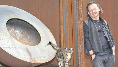 Der Bildhauer und Stahlplastiker Andreas Reichlin mit seiner Katze Butzi neben einem original Feuerring (Bild: Edith Meyer)