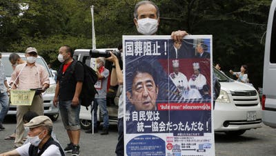 Ein Demonstrant hält ein Plakat mit dem Bild des ehemaligen Premierministers Shinzo Abe und fordert die Absage des Staatsbegräbnisses. (Yuri Kageyama / AP)