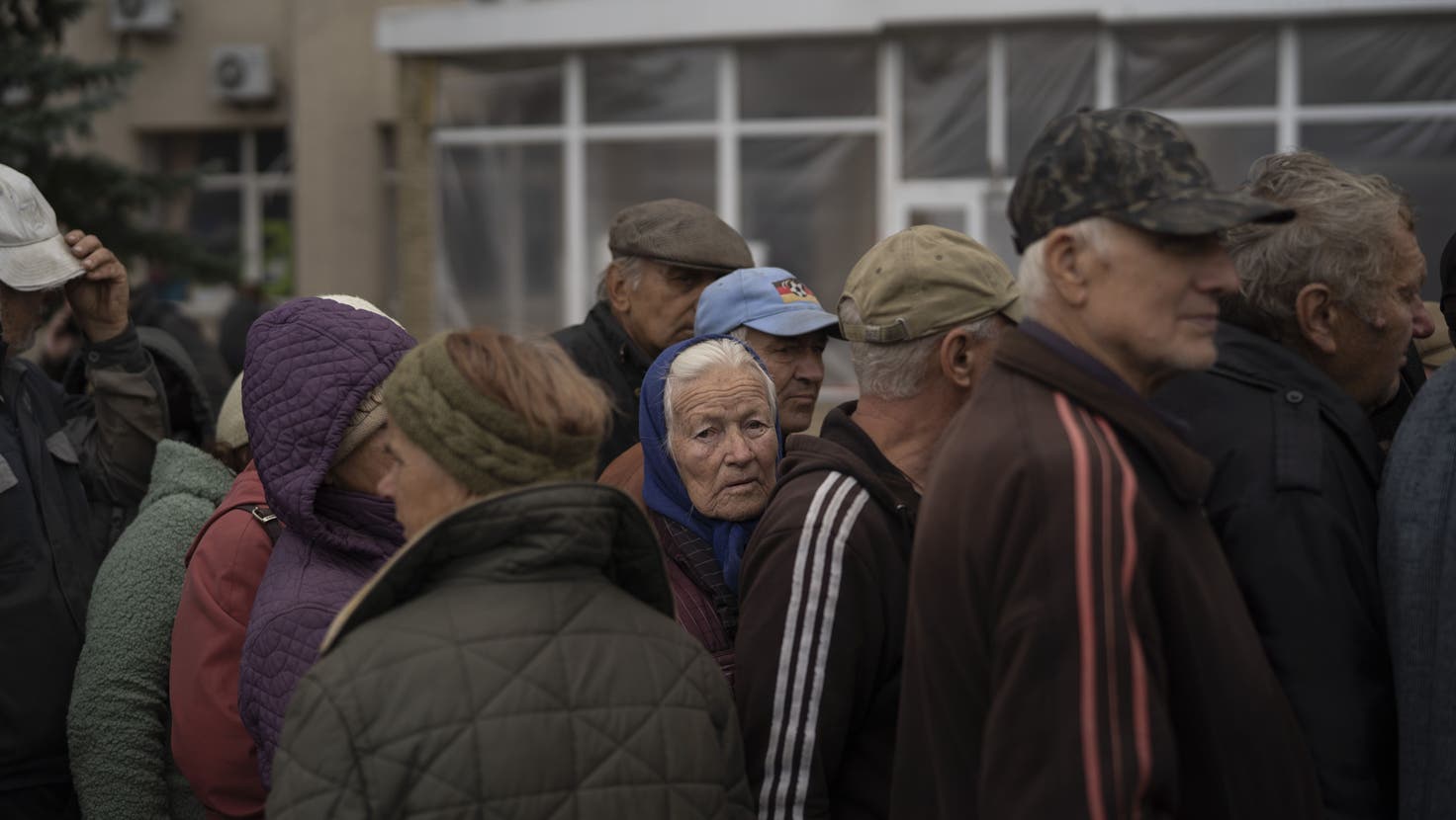 Menschen warten in einer Schlange, während in der zurückeroberten Stadt Lyman in der Ukraine humanitäre Hilfe verteilt wird. (Leo Correa / AP)