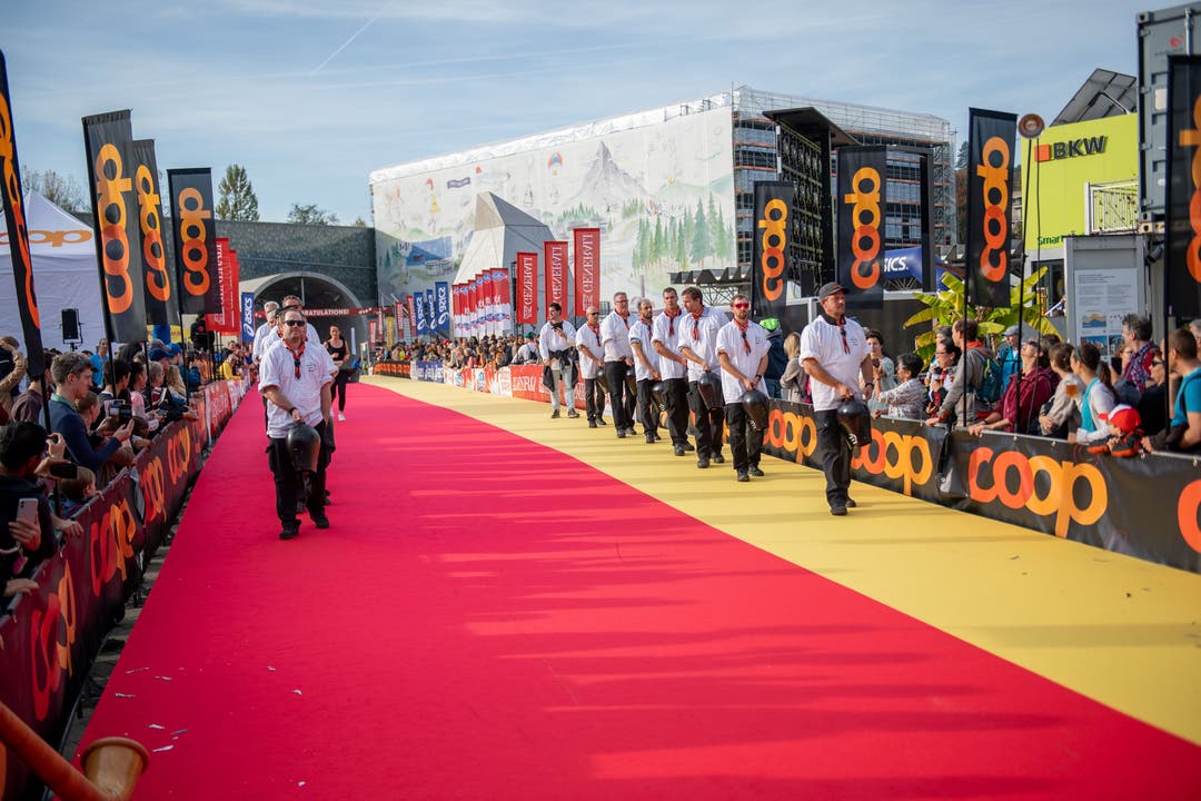 Auch Trychler gehen über den Teppich, wo tausende Läuferinnen und Läufer ihren Lauf beendet haben.