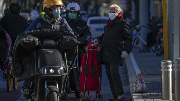 Eine ältere Frau ist mit ihren Einkäufen in Peking unterwegs. Die strenge «Null Covid»-Politik hat Ansteckungswellen in China bisher praktisch verhindert. Jetzt müssten viel Ältere sich impfen lassen. (Andy Wong / ap)