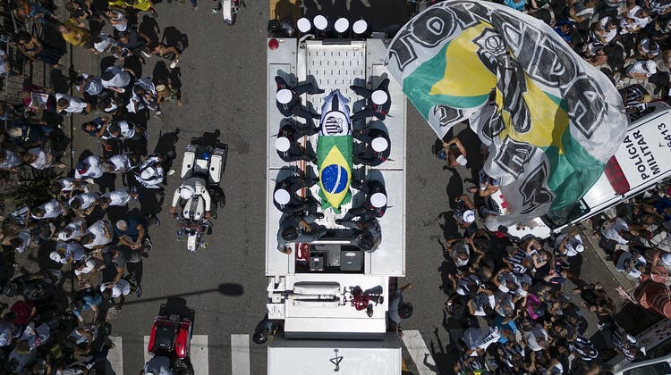The casket of late Brazilian soccer great Pele is draped in the Brazilian and Santos FC soccer club flags as his remains are transported from Vila Belmiro stadium, where he laid in state, to the cemetery during his funeral procession in Santos, Brazil, Tuesday, Jan. 3, 2023. (AP Photo/Matias Delacroix) (Matias Delacroix / AP)