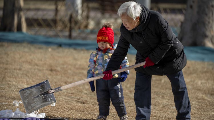 Ein älterer Mann und ein Kind schaufeln Schnee in einem Park in Peking. (Mark Schiefelbein / AP)