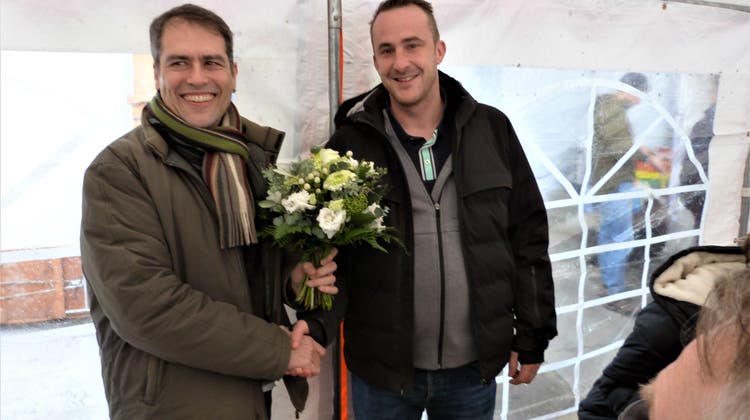 Dorfmarkt-Präsident Roland Hollenstein erhält von Gewerbepräsident Patrick Bitzer Blumen überreicht. (Bild: Kurt Lichtensteiger)