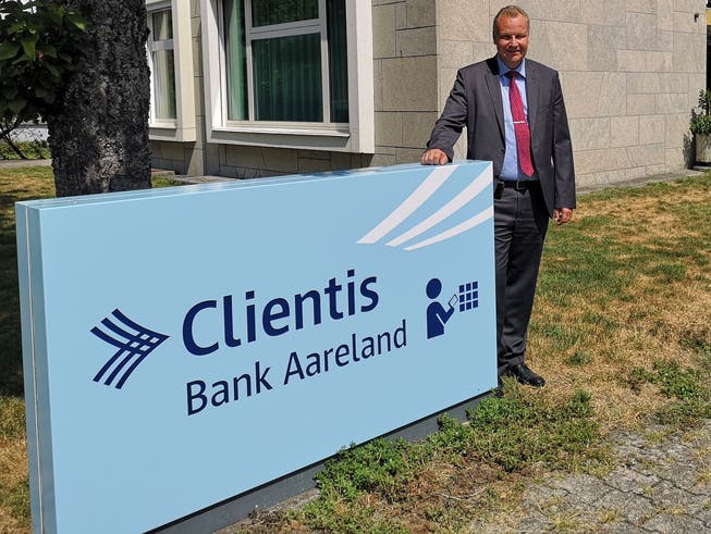 Hansjörg Gloor, Vorsitzender der Geschäftsleitung der Clientis Bank Aareland, mit dem Logo der Bank.