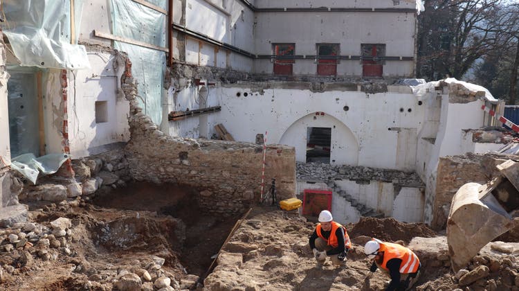 Im Erdreich stossen die Archäologen auf Mauern und Böden der ehemaligen Westtraktkeller, hinten stehen zwei Wände der alten Turnhalle. (Philipp Zimmermann)