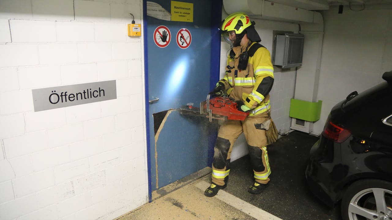 Ein Feuerwehrmann der Freiwilligen Feuerwehr Zug verschafft sich Zugang zum Technikraum hinter der Wand.