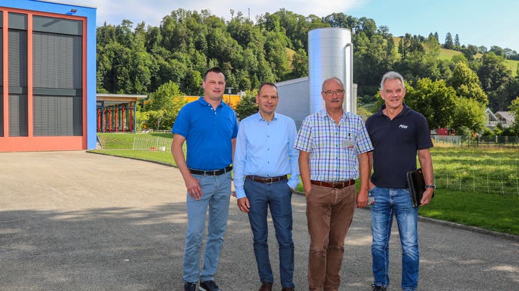 (V. l.) Roland Roos und Stephan Wolf (Bell Schweiz AG), Urs Lustenberger (Gemeinderat Zell) und Marcel Kränzlin (AEW Energie AG) vor dem Wasserspeicher des Wärmeverbunds in Zell. (Bild: zvg)