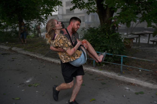 A man carries an injured woman after a second rocket exploded in the city of Pokrovsk.
