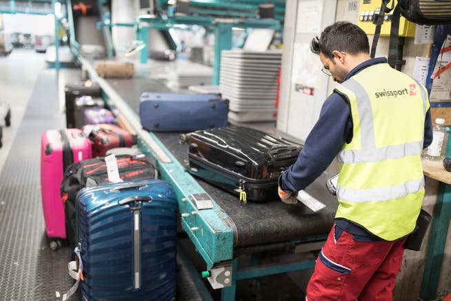 Ein Swissport-Angestellter sortiert die Gepäcke der Passagiere am Flughafen Zürich.