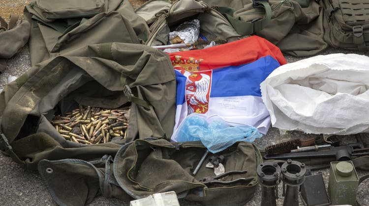 Eine serbische Flagge neben verschiedenen Waffen. (Symbolbild: AP)