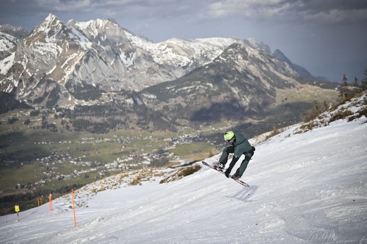 Ein Snowboarder in der Abfahrt vom Chäserrugg, mit Blick auf den Schafberg, im schneearmen Winter 2023.